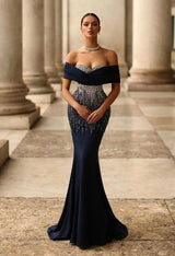 Woman in a black and silver evening gown standing in front of classical columns.